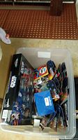 Plastic tote filled with Star Wars toys, some individually packaged and boxed Micro Machines set.