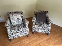 Pair of armchairs shown side by side with patterned fabric and different throw pillows.