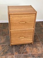 Front view of the wood veneer 2-drawer dresser showing the full piece on a tile floor.