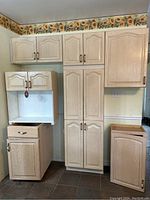 Front view of assembled kitchen cabinet units including base cabinets with drawers and countertop, tall pantry cabinet, and wall cabinets above.