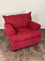Front angled view of oversized red armchair showing removable cushions and rounded armrests.