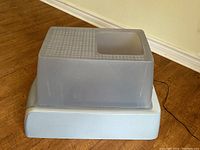 Photo of the taupe-colored removable hood with textured step area, positioned on top of the light gray base unit showed from side view.