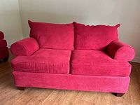 Front view of red loveseat with removable cushions, showing two seat cushions and two back cushions, with rounded armrests and wooden legs.