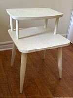 Full view of the vintage white painted two-level nightstand or end table showing its size and shape.