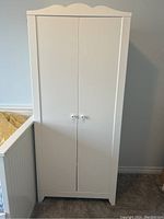 Front view of white IKEA SMAGORA wardrobe with scalloped top edge and two doors closed