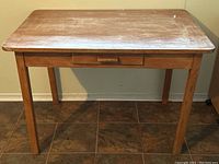 Front view of the wood desk showing rectangular top, legs, and small drawer underneath.