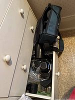 Open drawer showing camera bag, filters in plastic bag, lens and camera cases