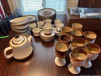 Wide view of all Denby dishes, teapot, and pottery goblets arranged on table