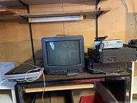 Photo showing Sony Trinitron 13-inch CRT TV, Canon Canoscan scanner, and other electronics stacked on a wooden surface