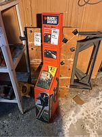 Boxed Black & Decker 16 inch hedge trimmer standing upright in basement next to shelving and wood.
