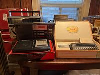 Lot showing three portable radios and Craig Translator with tapes on a wooden table.