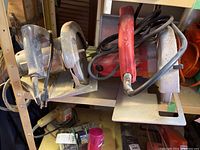 Two circular saws on a shelf with visible wear and cords coiled around them.