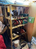 Front view of four-tier metal utility shelving unit with various tools on shelves, not included in sale.