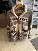 Front view of hand knit wool sweater coat on hanger showing zipper closure and moose pattern