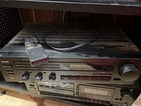 Front view of the black TEAC stereo receiver with remote placed on top. Shows front buttons and knobs for controls.