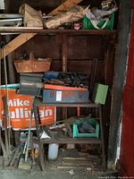 Photo showing shelving with assorted tools including metal toolbox and garden signage in background.