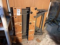 Folding work table folded with wood top visible, showing wear and scratches. Metal base visible, highlighting folding mechanisms and condition.