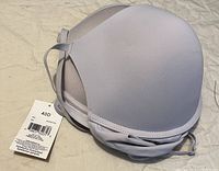 Close-up photo of a new white padded bra size 40D with original tag attached, showing fabric and strap details.