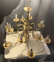 Top-down view of the brass chandelier displaying ten curved arms with candle-style light holders and central decorative column.