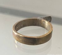 Close-up photo of the copper ring showing the square band shape and surface details with wear marks.