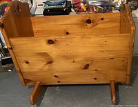 Side view showing full length of the pine cradle with curved rocking base and visible wood knots
