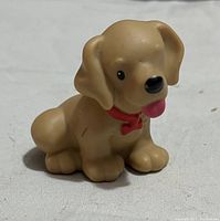 Photo of a small beige PVC dog figure, seated with red collar and tongue out, smooth surface with minor wear.