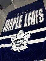 Dark blue plush throw blanket with large white 'Toronto Maple Leafs' text and leaf logo in the center.