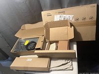 Boxed IKEA INREDA under-desk drawer kit and miscellaneous boxes of electronic accessories and hardware components.