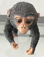 Top view showing detailed textured black fur, large eyes, and tan face and limbs of monkey figurine.