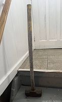 Full-length view of the sledgehammer showing wooden handle and metal hammerhead.
