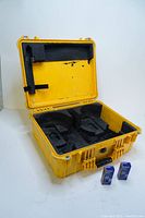 Open yellow Pelican case showing interior foam inserts and two new Brady lock boxes placed next to it.