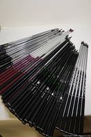 Top view showing 81 golf shafts arranged side-by-side on a white surface, displaying various materials and grip colors.