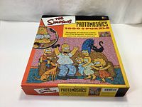 Closed box of The Simpsons 1000-piece photomosaic jigsaw puzzle showing cover artwork with family portrait made of many miniature images.