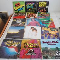Overview of 15 vintage LP records laid out on a white cloth surface, showing variety of 1970s music compilations and Bee Gees albums