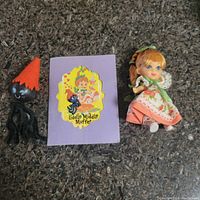 Photo of Little Miss Muffet doll, spider figurine, and booklet on textured surface.