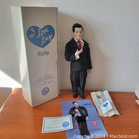 Full view showing the boxed Ricky Ricardo doll, its stand, certificate, poster, and paper materials on display.