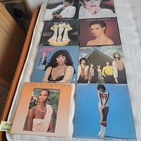 Eight classic 1980s vinyl LP album covers arranged flat on a bed showing Michael Jackson, Barbra Streisand, Sheena Easton, Donna Summer, Whitney Houston, Air Supply and Melissa Manchester