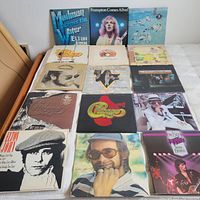Four-by-four grid of album covers laid out on bed surface