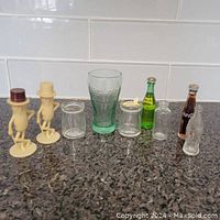 Full view of all miniature collectibles including two Mr. Peanut figurines with hats, small glass jars, a Coca-Cola glass, and two miniature glass bottles.