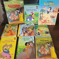 Full group shot of 9 vintage Disney children's storybooks arranged on a wooden surface, featuring Snow White, Bambi, Lady and the Tramp, The Jungle Book, and Goofy titles.