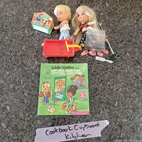 Two blonde-haired Liddle Kiddles dolls, red wagon, Liddle Kiddles Klub house, green storybook, doll shoes, combs, black stand, plastic bag on carpet