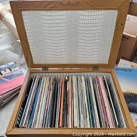 Opened footstool showing interior lined with patterned material and collection of vinyl LP records stored vertically inside.
