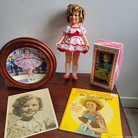 Full view of Shirley Temple dolls, collector plate, autographed photo, and book on wooden surface