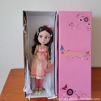 Doll seated in white inner box with pink decorative outer sleeve labeled “Patience”