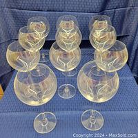 Front view showing 11 oversized clear red wine glasses arranged on blue fabric.