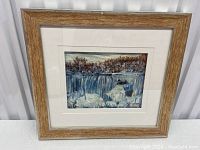 Front view of the framed oil painting depicting American Falls with icy features, showing the wood-tone frame and white matting.