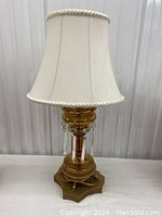 Full front view photo of the lamp showing the brass base, amber etched glass body with hanging crystals and cream fabric shade