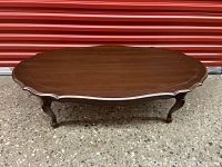Front view of traditional cherry wood coffee table showing scalloped edges and cabriole legs.