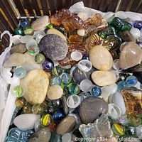 Close-up of stones, marbles, and glass figurines inside a wicker basket showing a variety of colors and textures.