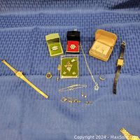 All jewelry items displayed on blue fabric background showing rings, earrings, wristwatches, necklaces, and pins.